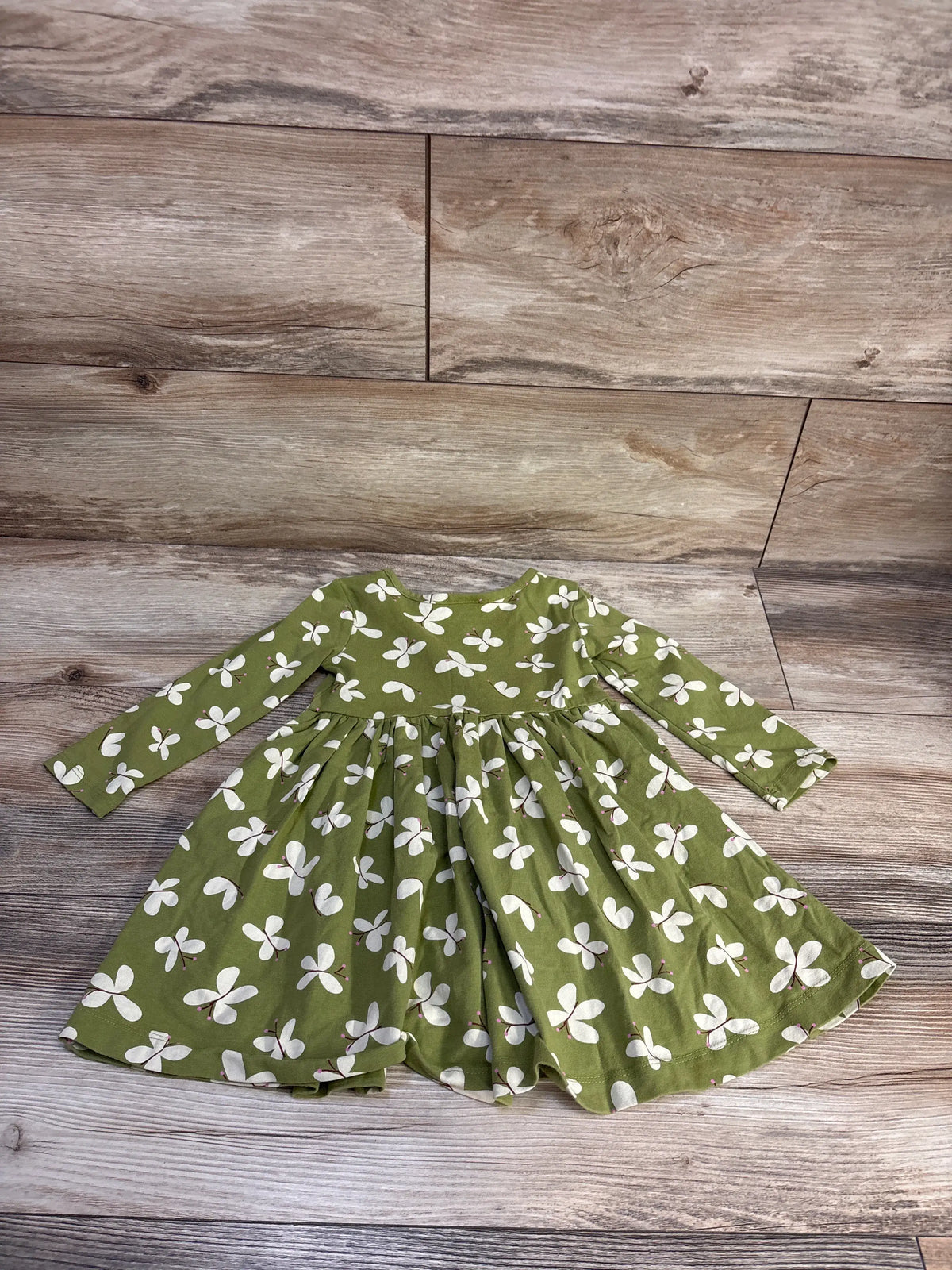 Front flat lay of Hanna Andersson long-sleeve dress showing full skirt and white butterfly print on moss green on wood floor