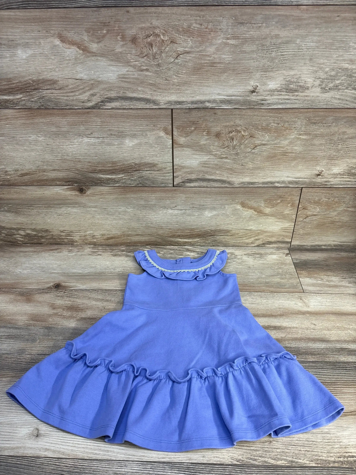 Top-down view of purple Janie and Jack ponte dress (3T) showcasing ruffled collar with circle trim and ruffled hem on wood plank background