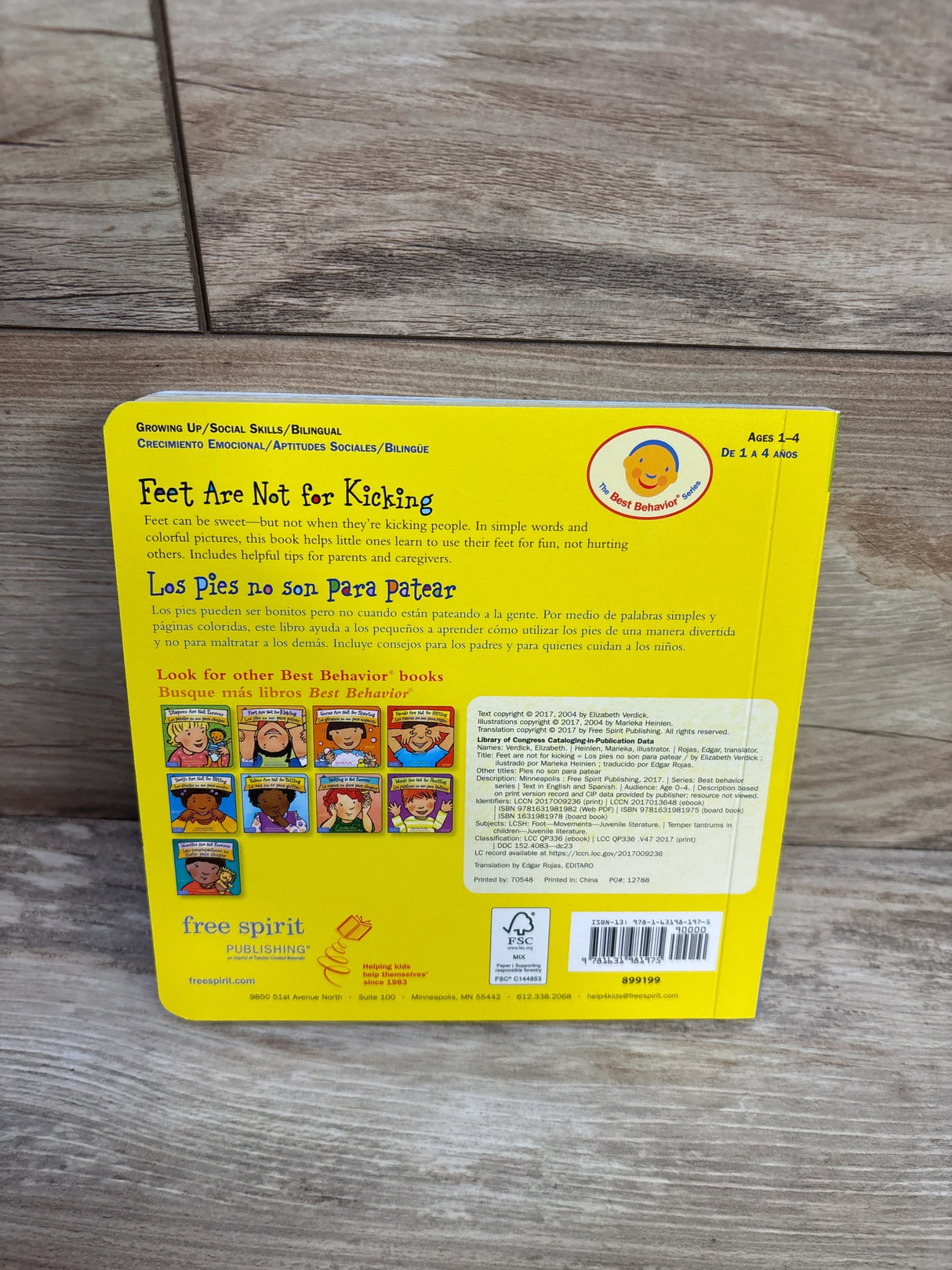 Back cover of Feet Are Not for Kicking bilingual children's book on wooden floor