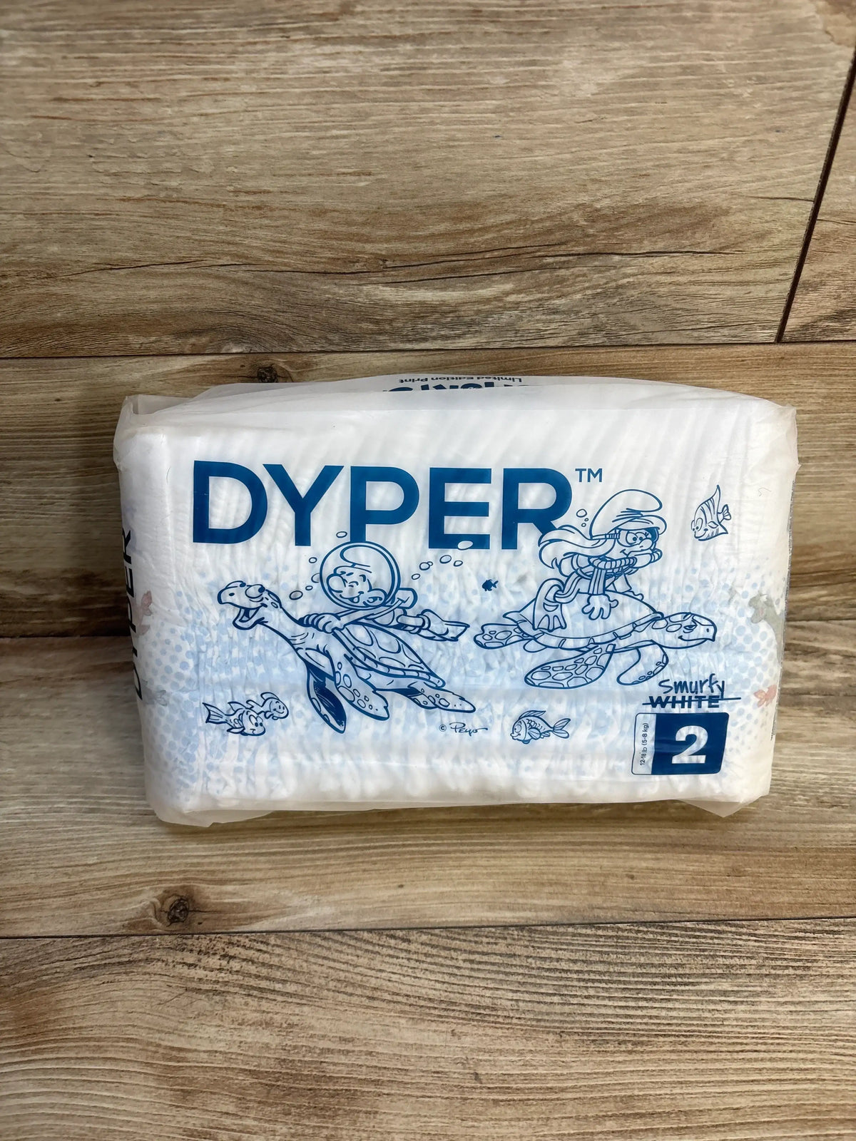 Dyper Smurfy White size 2 eco-friendly diapers with Smurfs design on wooden surface