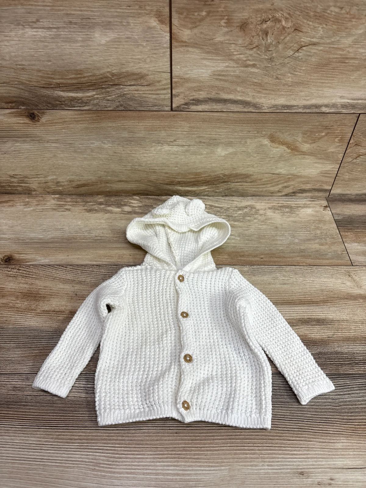 Front view of Carter’s white knit hooded sweater in size 3m showcasing textured knit and button front with wooden background