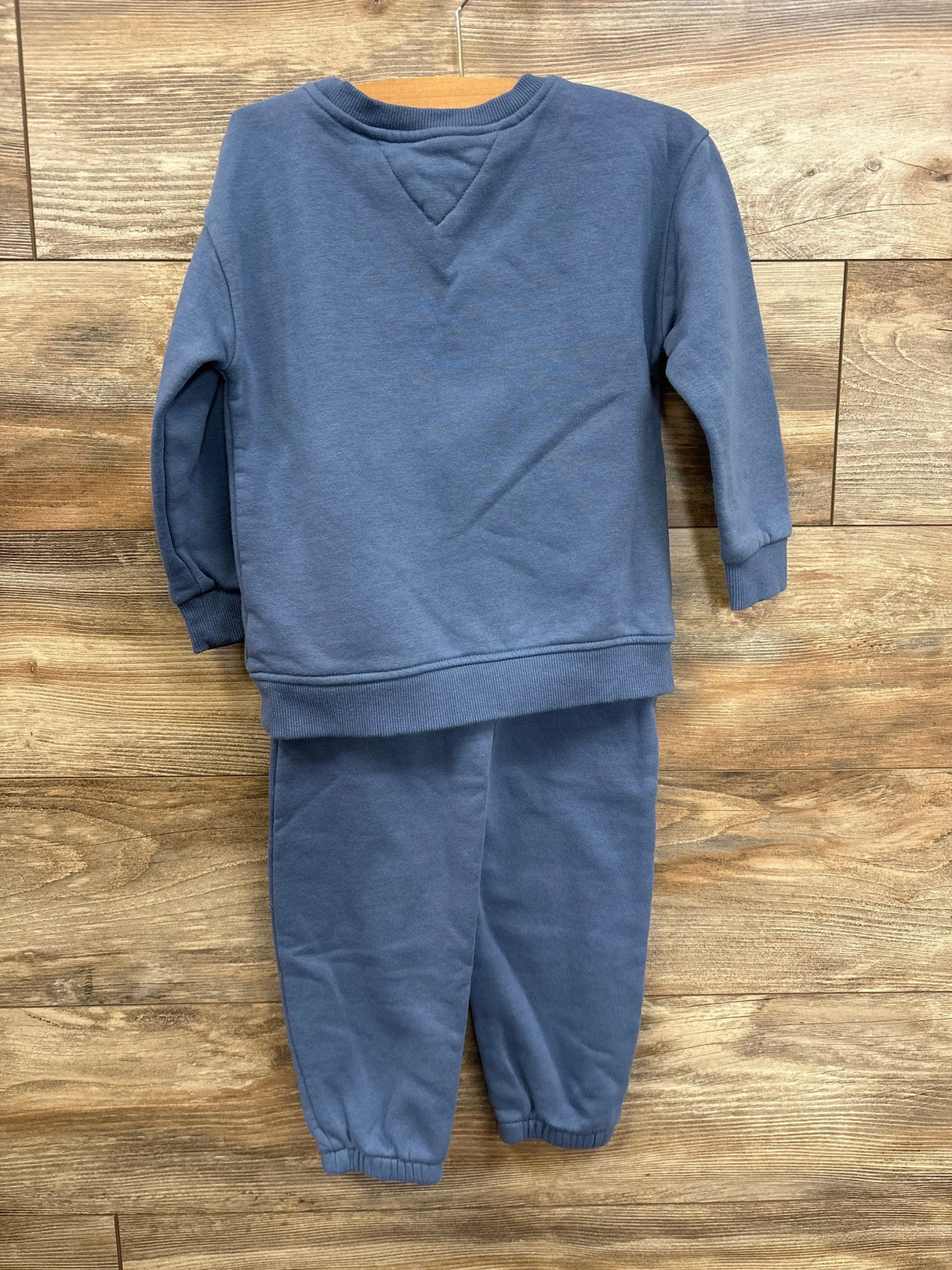 Blue toddler sweatshirt and sweatpants set displayed on wooden background