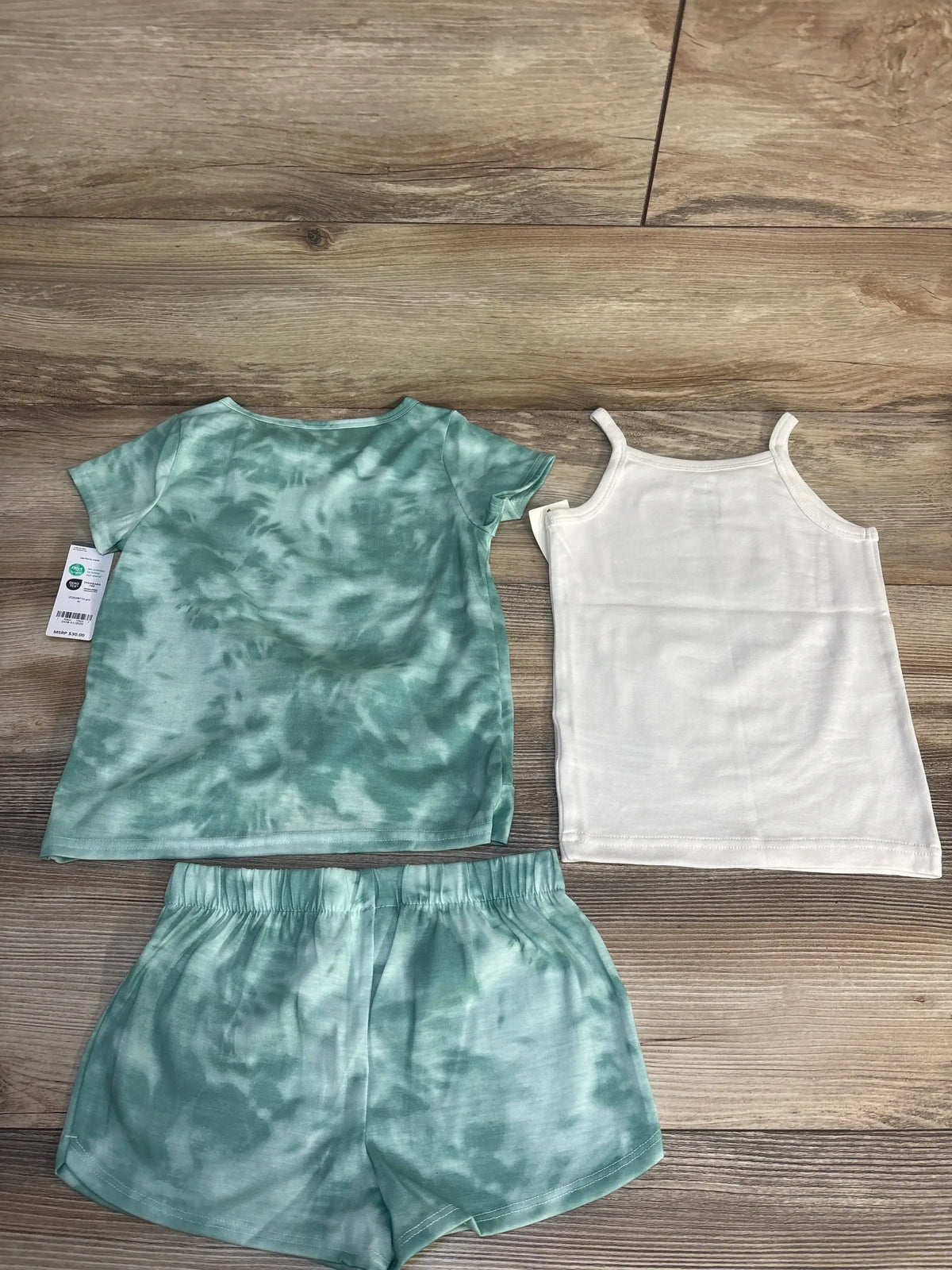 Kids green tie-dye shirt and shorts set with a white tank top on wood floor