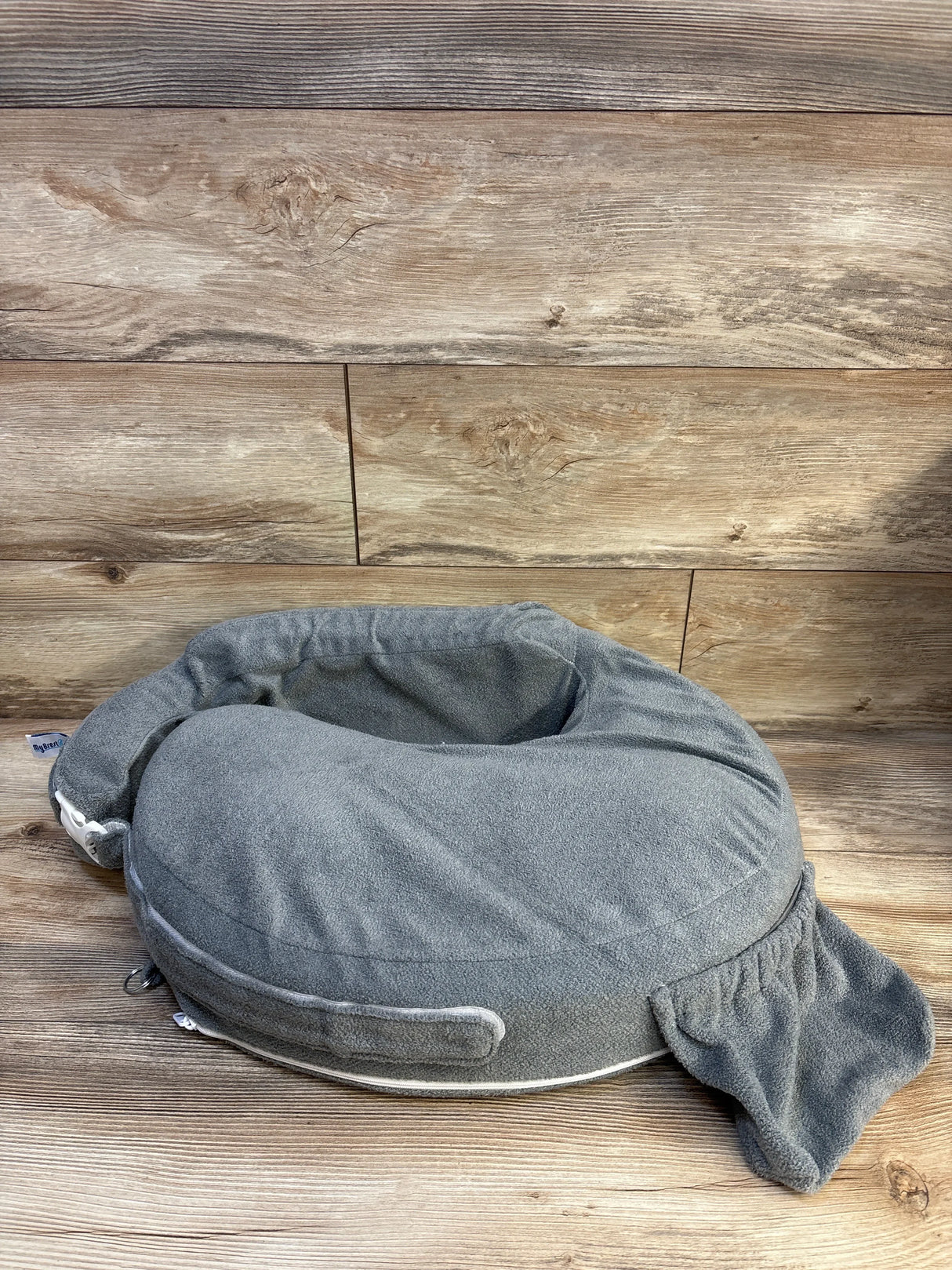 Front view of My Brest Friend nursing pillow in grey showcasing attached pocket and soft terry cover on wood floor