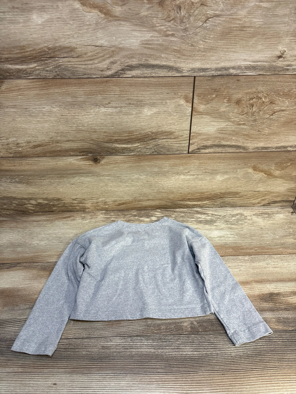 Gray long sleeve kids shirt laid flat on wood background, gently used children's clothing