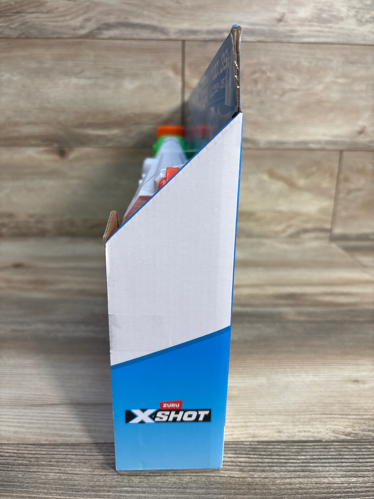Zuru X-Shot toy blaster packaging on wooden surface, side view