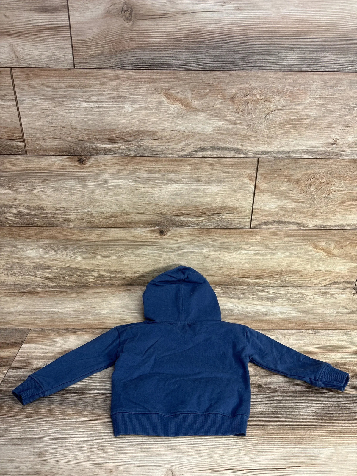 Navy blue children's hoodie with long sleeves on wooden floor background