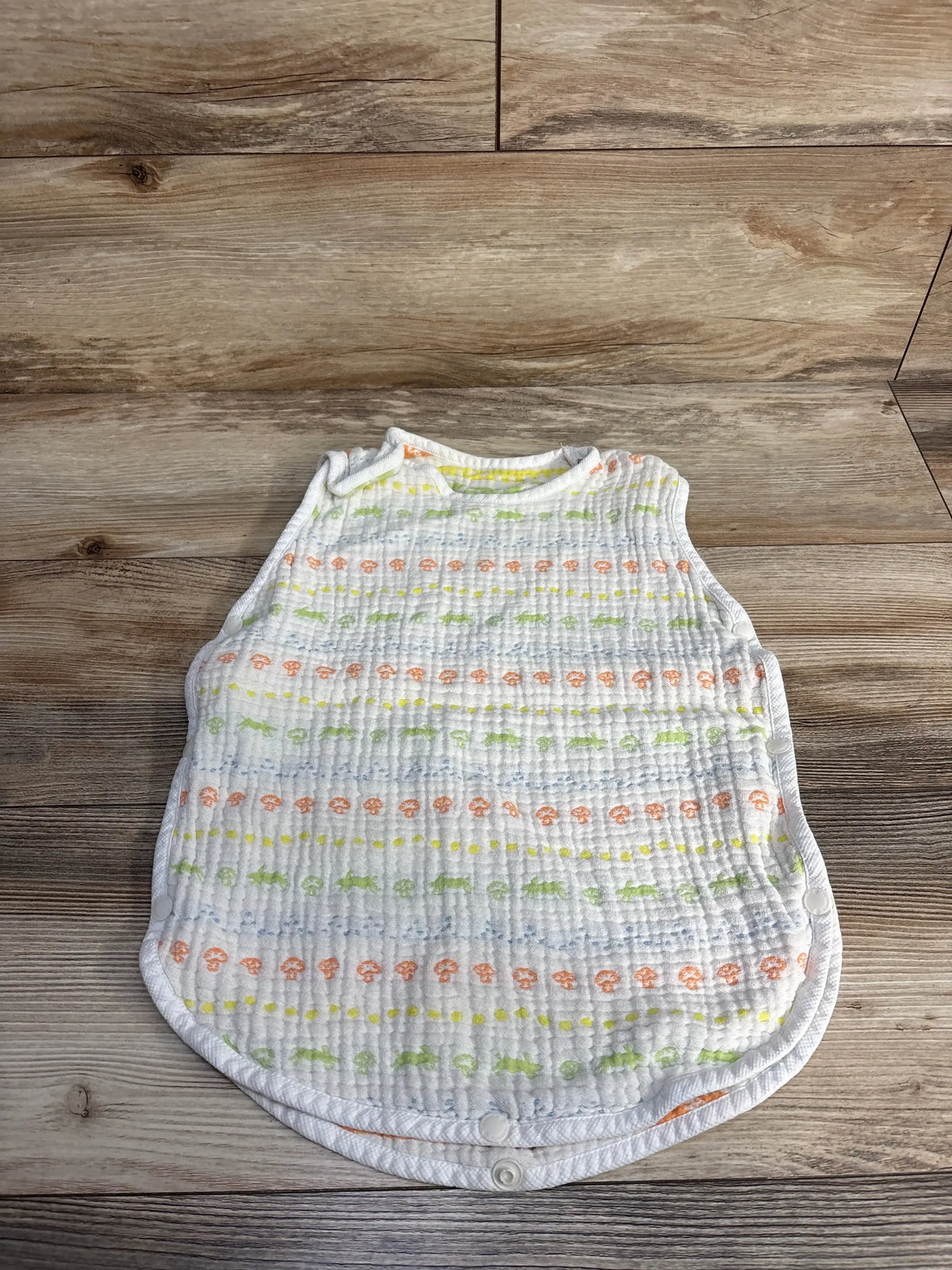 Soft baby sleep sack with animal print on wood floor, multicolor muslin wearable blanket