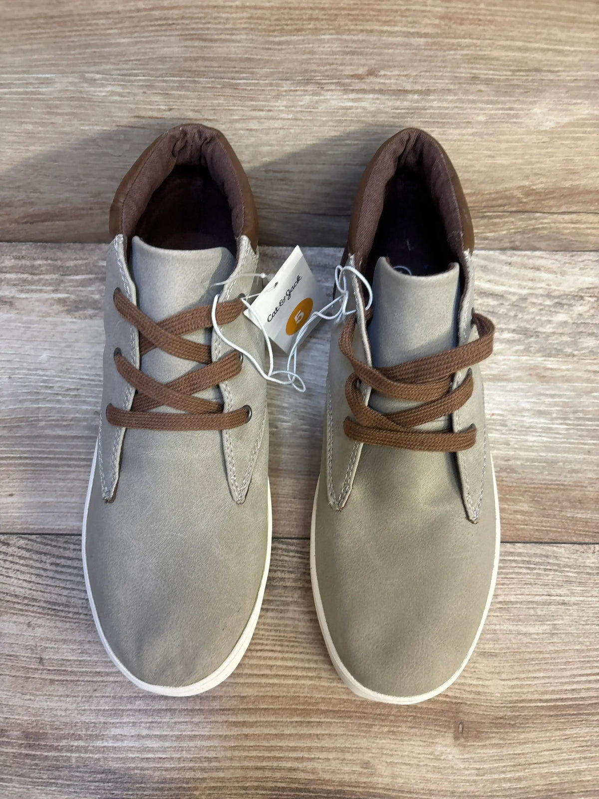 Top view of Cat & Jack Jakob kids’ gray high-top boots size 5Y showing brown laces and white soles on wooden surface