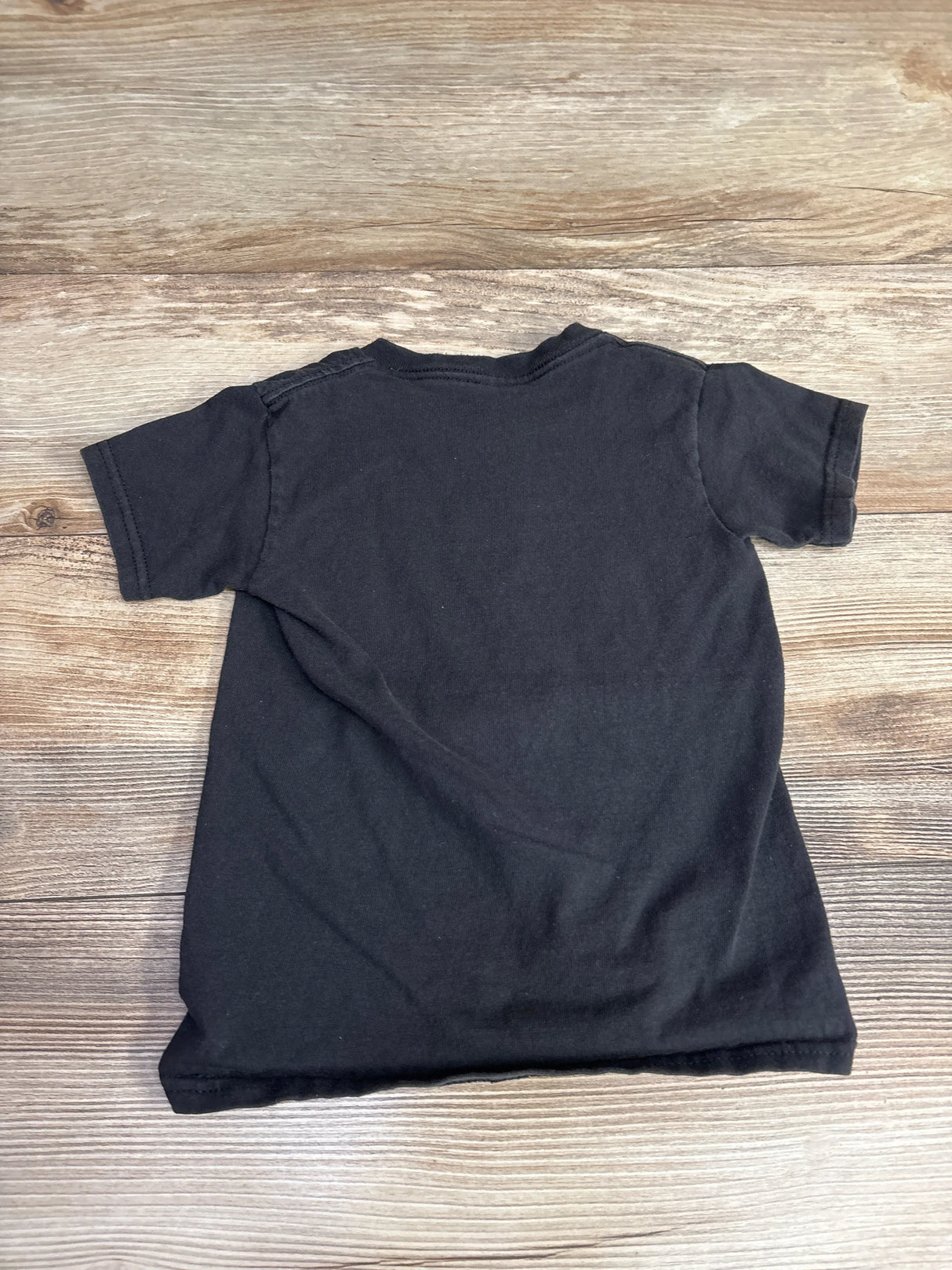 Back view of black Disney Rainbow Mickey Mouse toddler T-shirt (4T) showing plain back and short sleeves on wooden surface