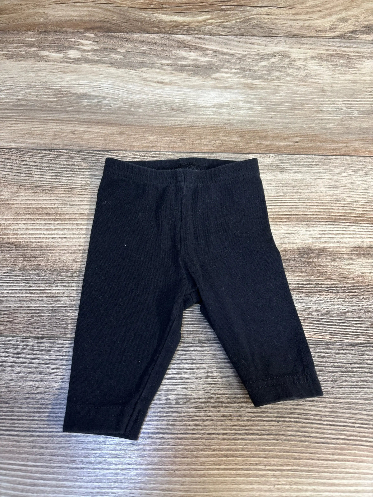 Black baby leggings on wood background, gently used kids clothing