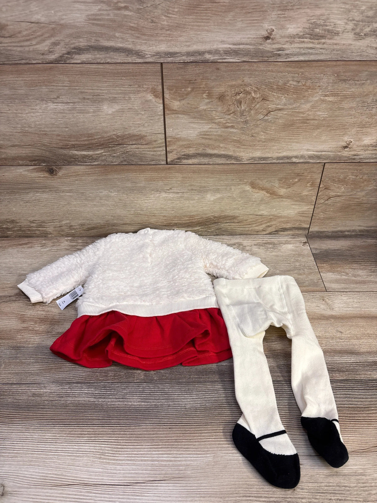 Front view of Minnie Mouse sherpa baby dress with red ruffle skirt and matching cream footed tights on wood background