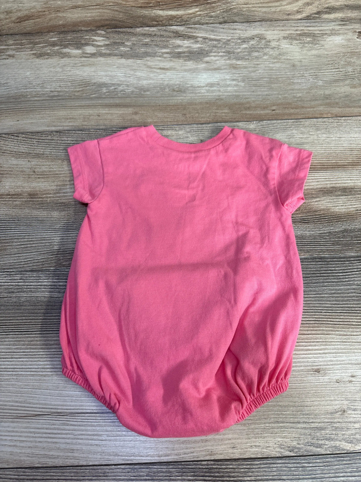 Front view of pink Okie Dokie butterfly bubble romper showing short sleeves and elasticized leg openings on wood grain