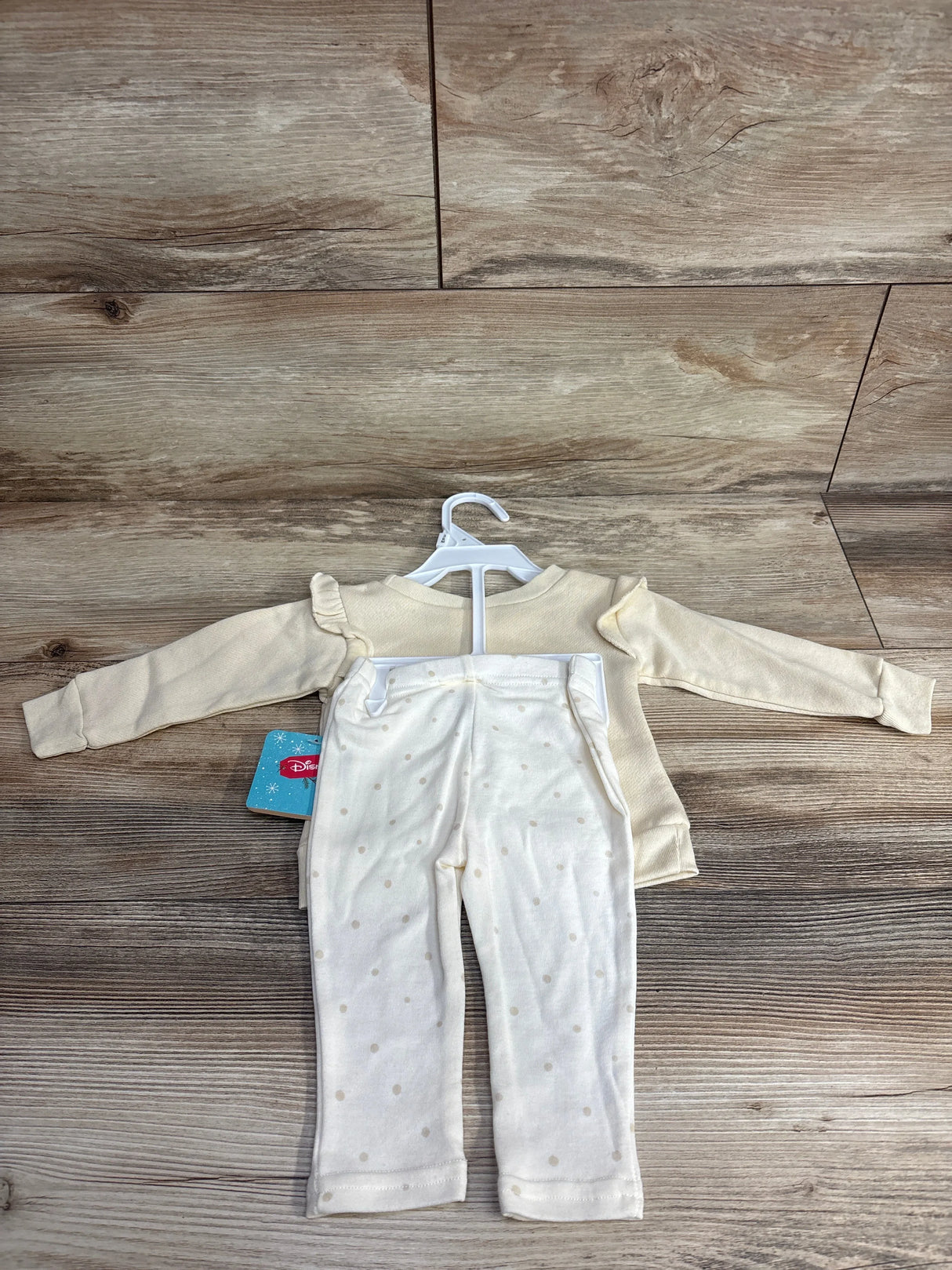 Cream long sleeve baby shirt and white polka dot pants set on wooden background