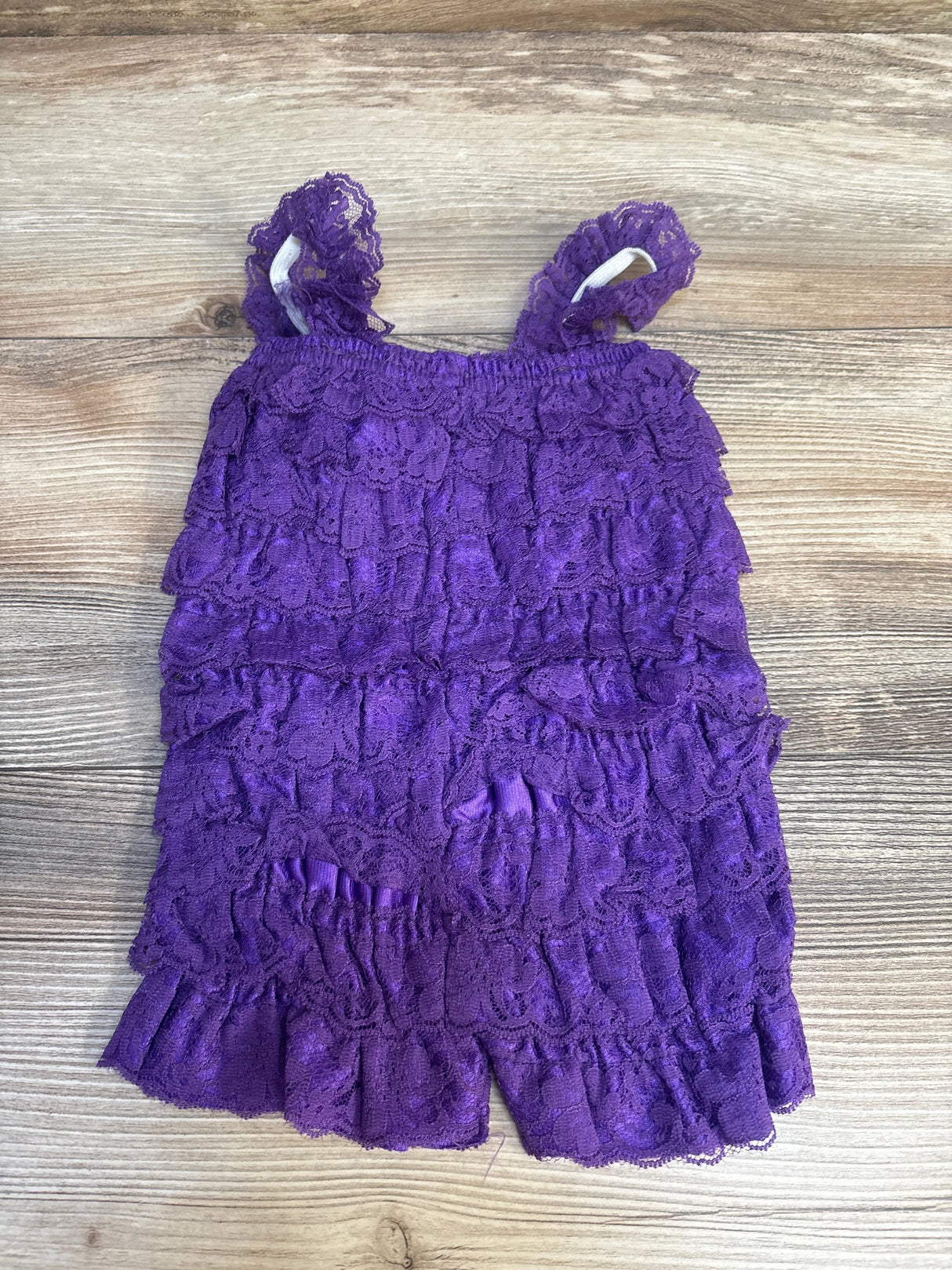 Purple lace ruffle toddler dress with shoulder straps on wood background