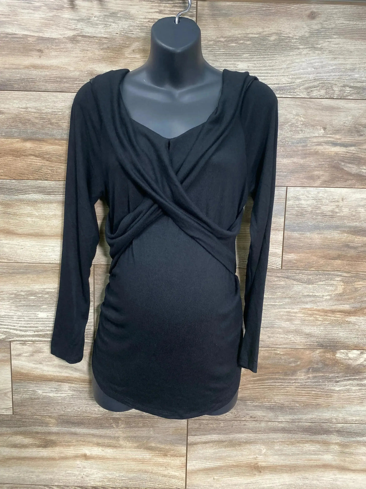 Front view of black Isabel maternity cross-front top size L, wrap bodice and ruched sides on mannequin with wood background