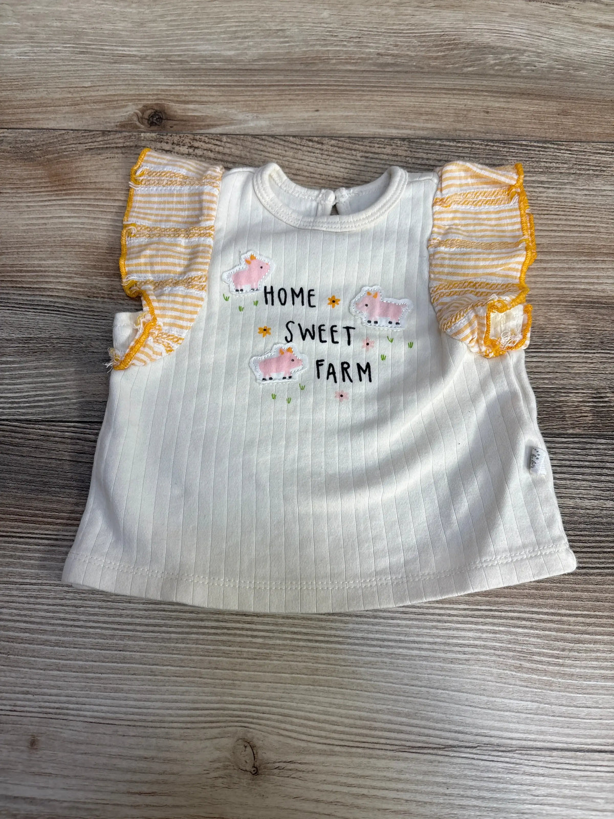 Front view of Exersaucer Home Sweet Home Shirt sz 3-6m in cream ribbed knit showcasing farm animal graphic and orange striped flutter sleeves on wood plank background