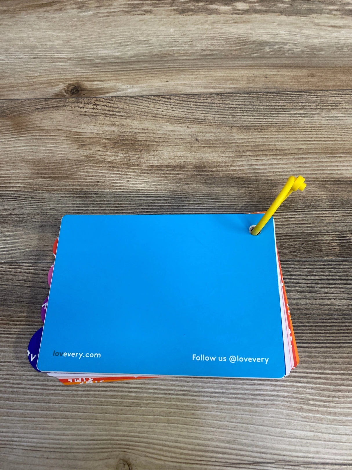 Lovevery blue flashcard with yellow ring on wooden table, educational baby toy