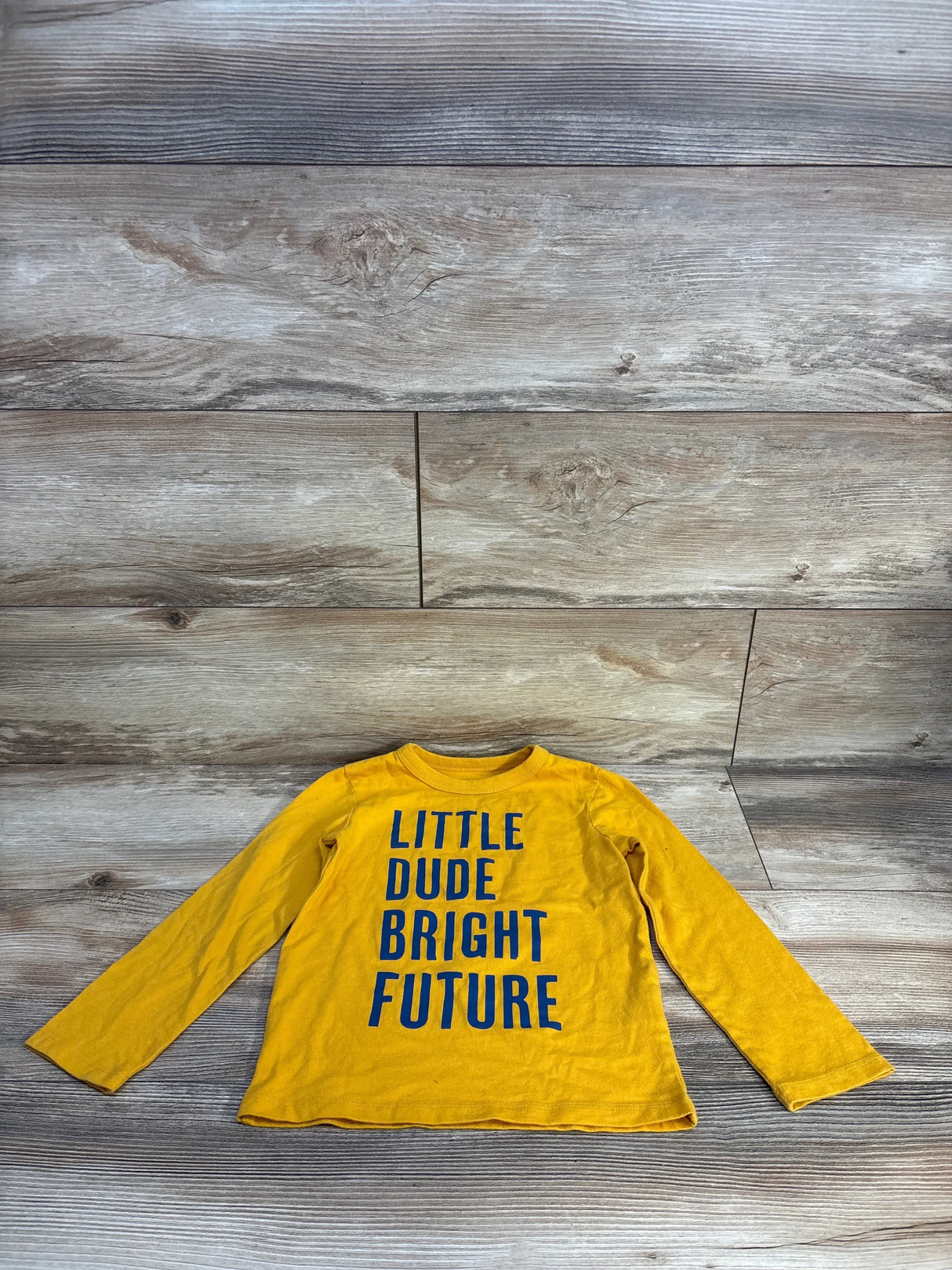 Yellow kids long sleeve shirt with 'Little Dude Bright Future' text on wood background