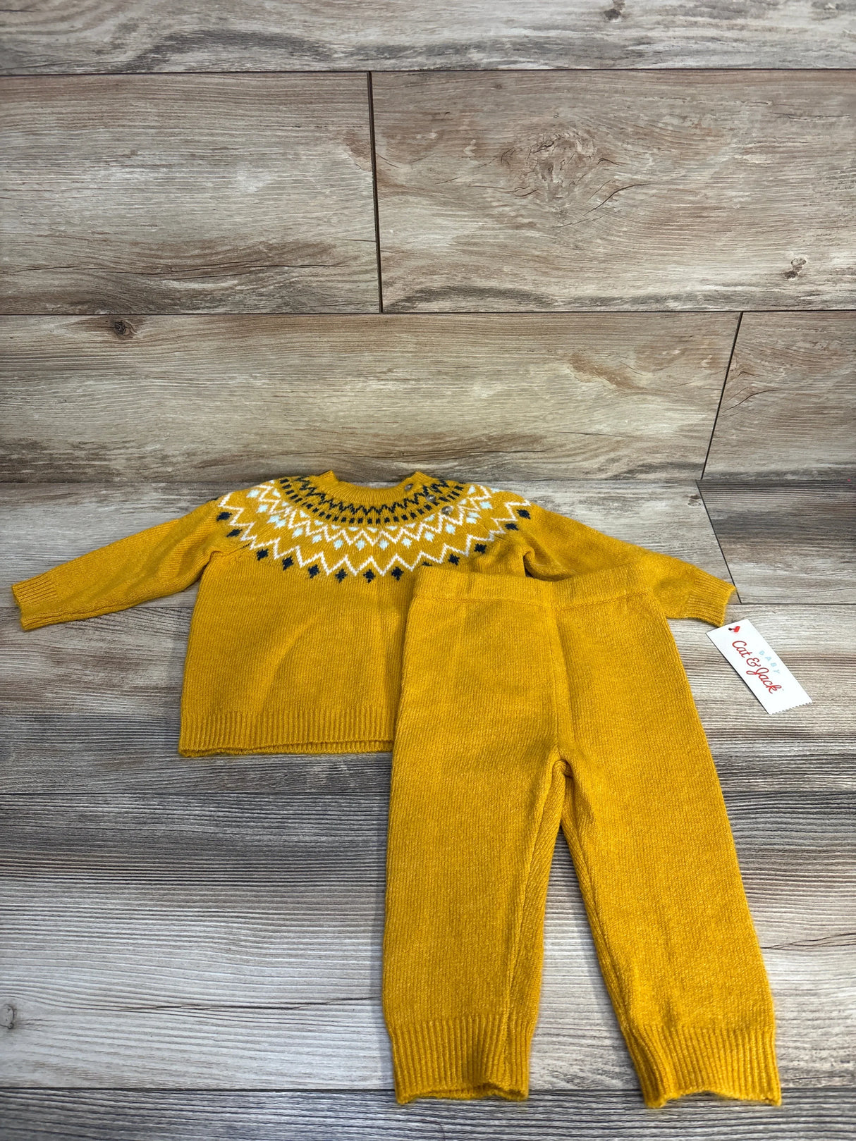 Yellow knit toddler sweater and pants set with geometric pattern on wood background