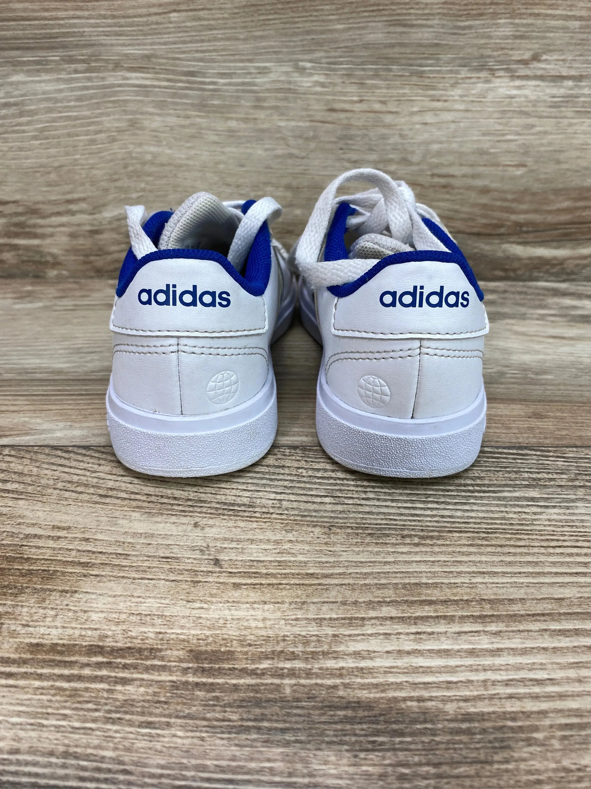Rear view of Adidas Neo Grand Court Base 2.0 sneakers in cloud white with royal blue heel collar and adidas logo on wood floor