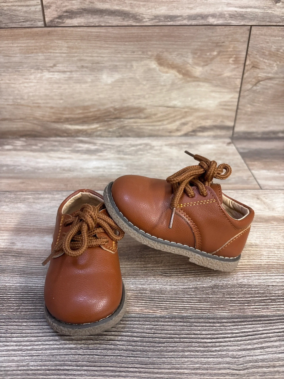 Front and side views of brown Meckior Oxford dress shoes showcasing lace-up closure and PU leather on a wood-look floor