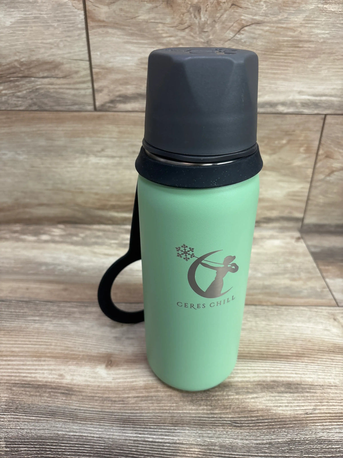 Front view of green CERES Chill OG Breastmilk Chiller showcasing black lid and handle on a wood-look surface