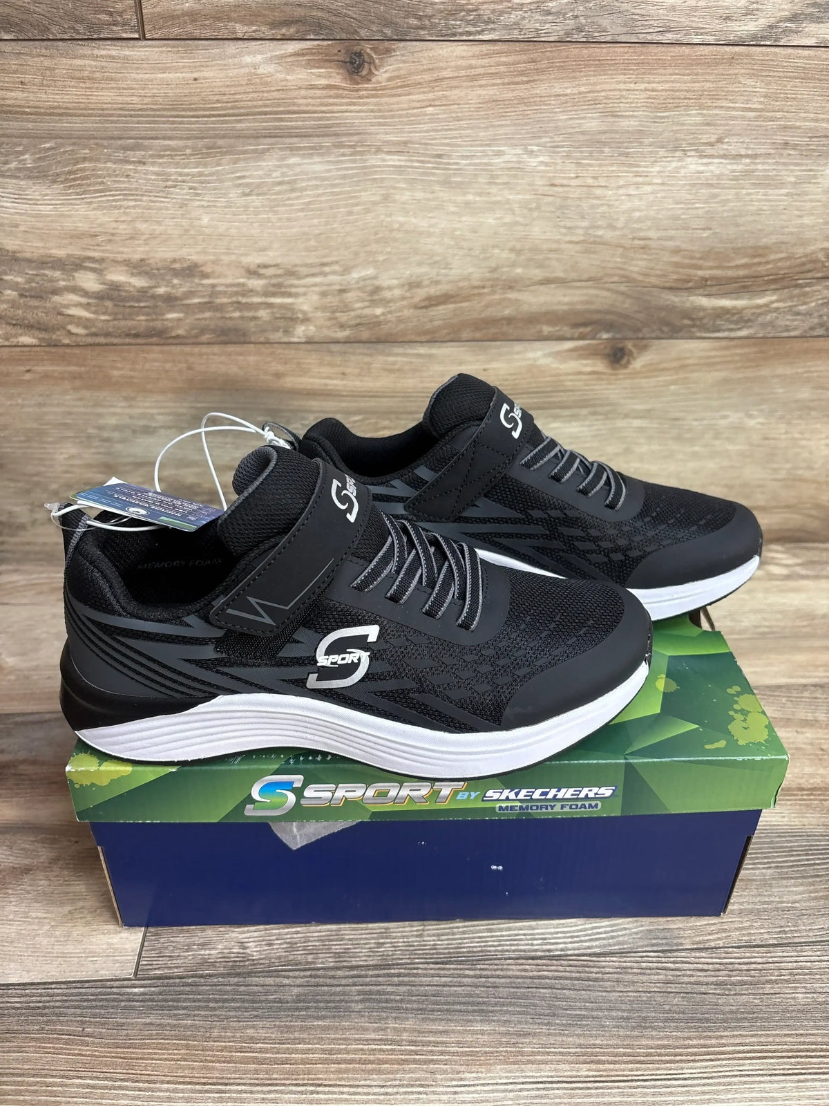 Black S Sport by Skechers sneakers with memory foam on box, wood background