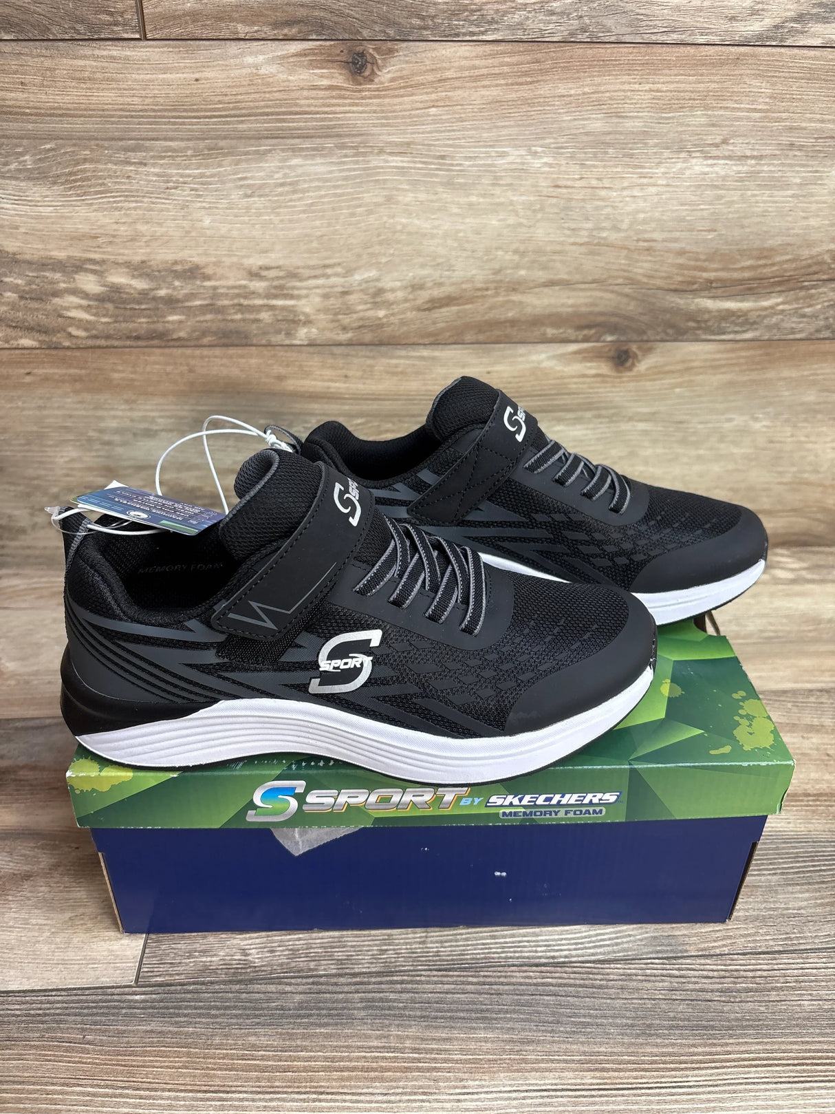 Black S Sport by Skechers sneakers with memory foam on box, wood background