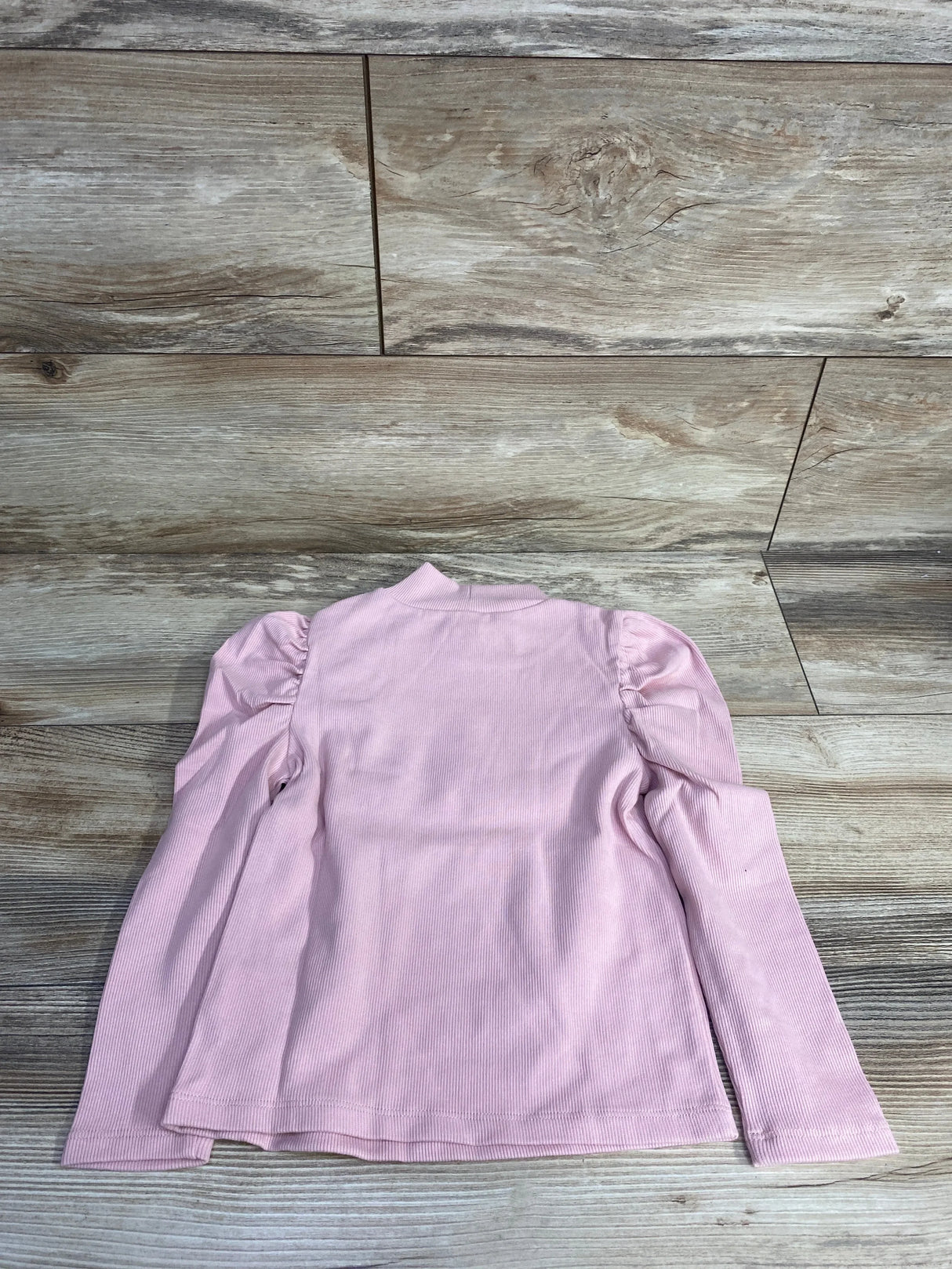 Light pink long sleeve girls shirt with puff shoulders on wood background