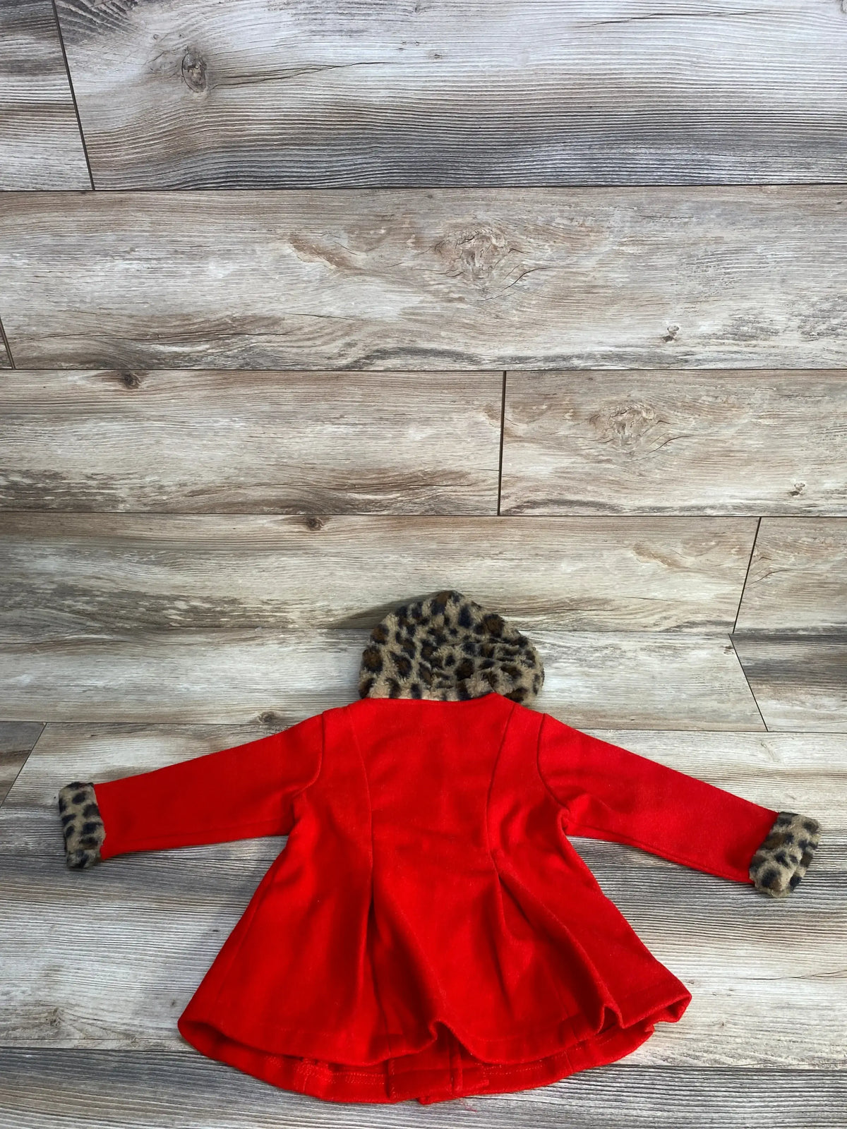 Red doll coat with leopard print hood and cuffs on wood background