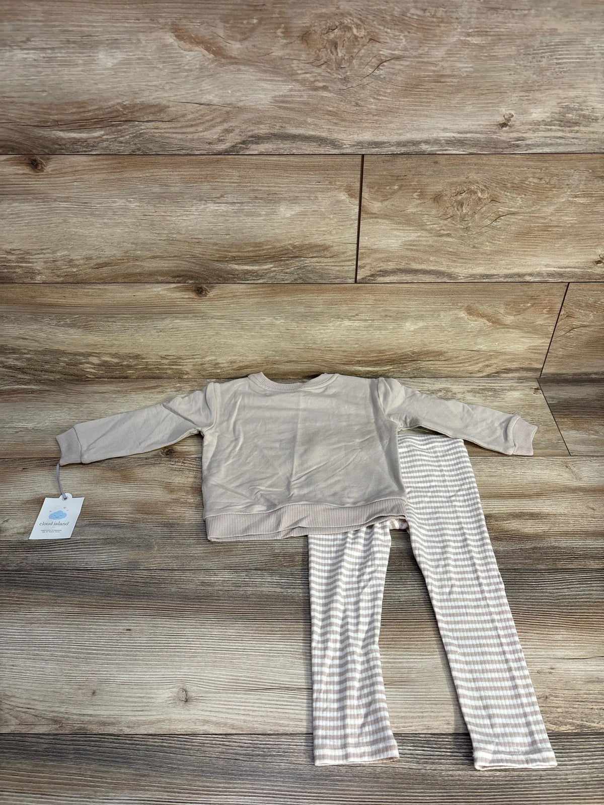 Top down view of Cloud Island Mama’s Mini beige sweatshirt and pants set in size 18 months with striped pants on a wood floor