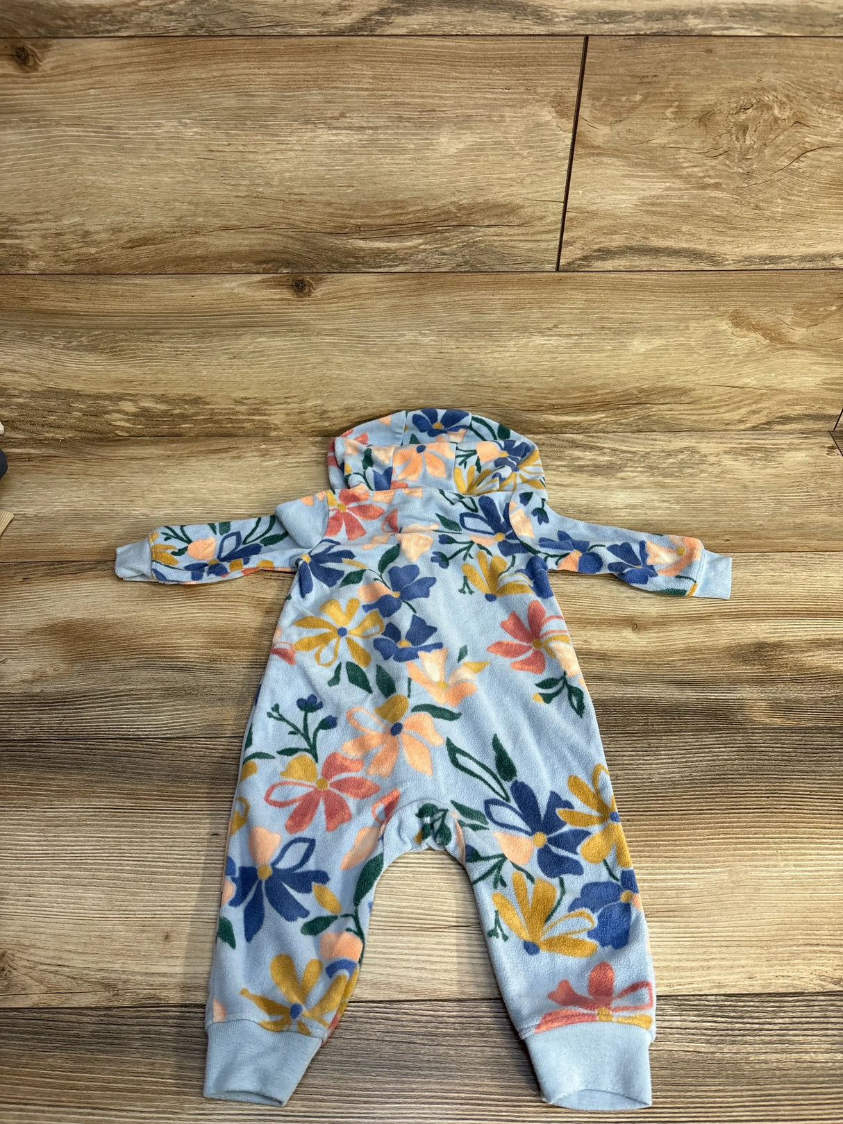 Floral patterned baby onesie with hood on wooden floor
