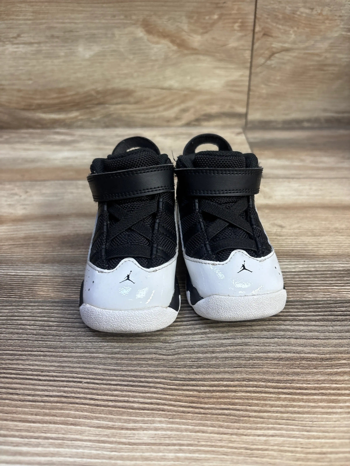 Front view of Air Jordan 6 Rings TD sneakers, size 4C, showcasing black and white uppers and hook-and-loop straps on a wood floor