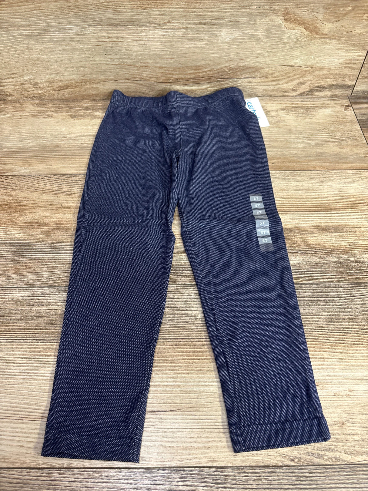 Flat lay of Carter's navy chambray toddler jeggings size 5T showing elastic waistband and slim leg on wood floor
