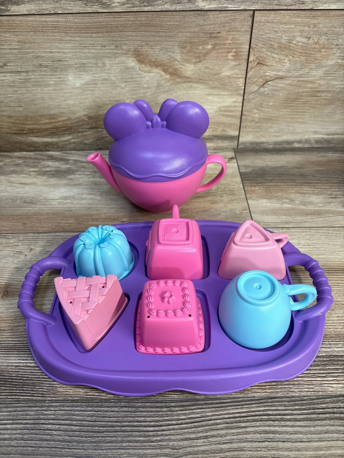 Front view of Minnie Mouse and Friends tea party set with pink and purple teapot, purple tray, three cups, and desserts