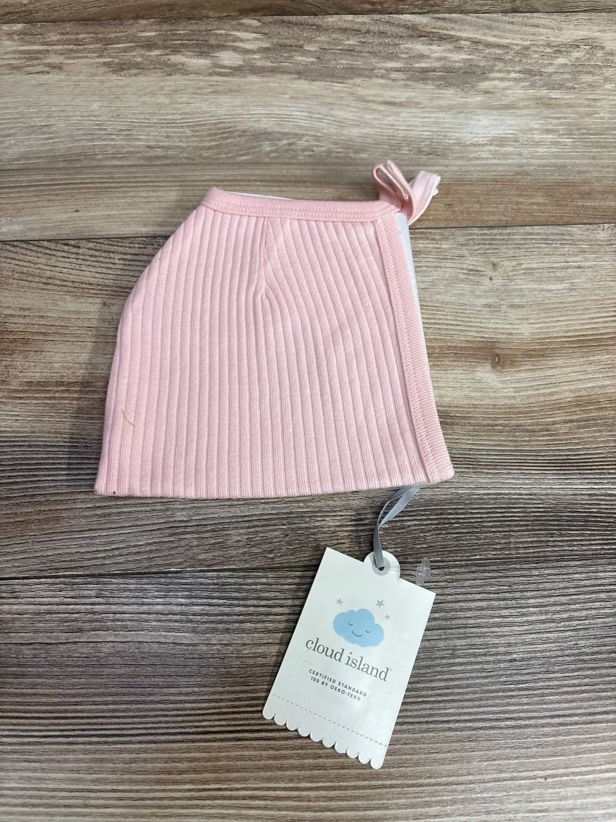 Pink ribbed baby hat with knot and Cloud Island tag on wood background