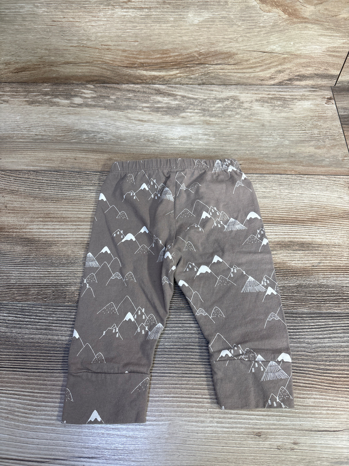 Back view of Baby Gap brown baby joggers showcasing white mountain print and elastic waistband on wood background
