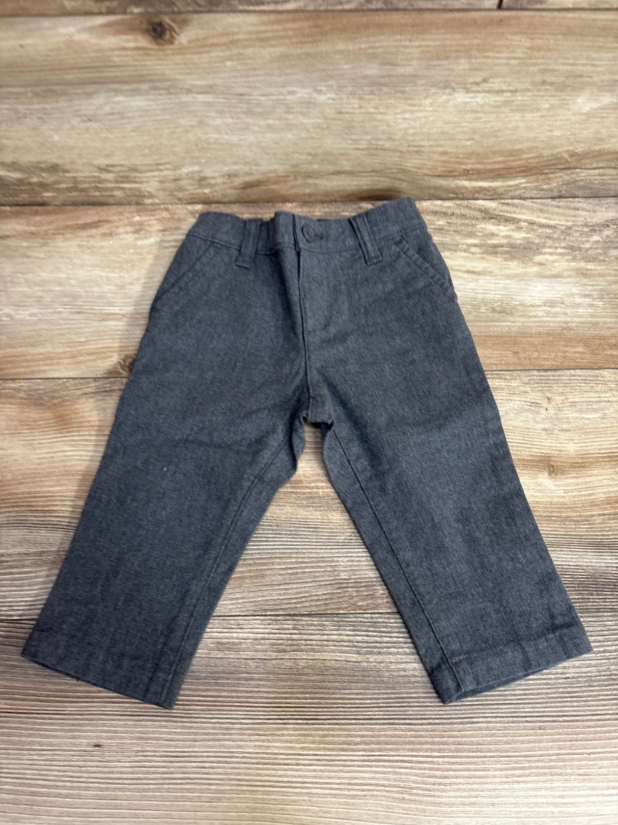 Children's gray dress pants laid flat on wooden surface for resale at kids clothing store
