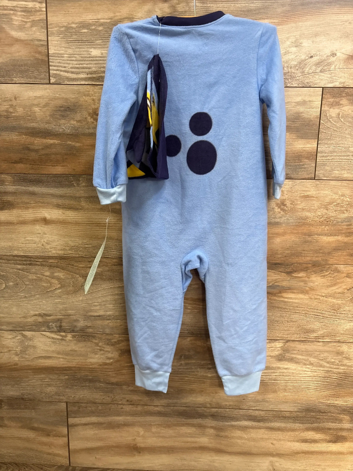 Front view of Bluey unisex hooded union suit pajamas in blue, showcasing footless legs and front graphic on wood floor