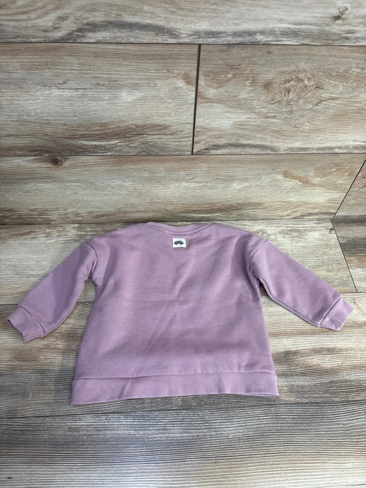 Light purple kids sweatshirt with long sleeves on wood floor background