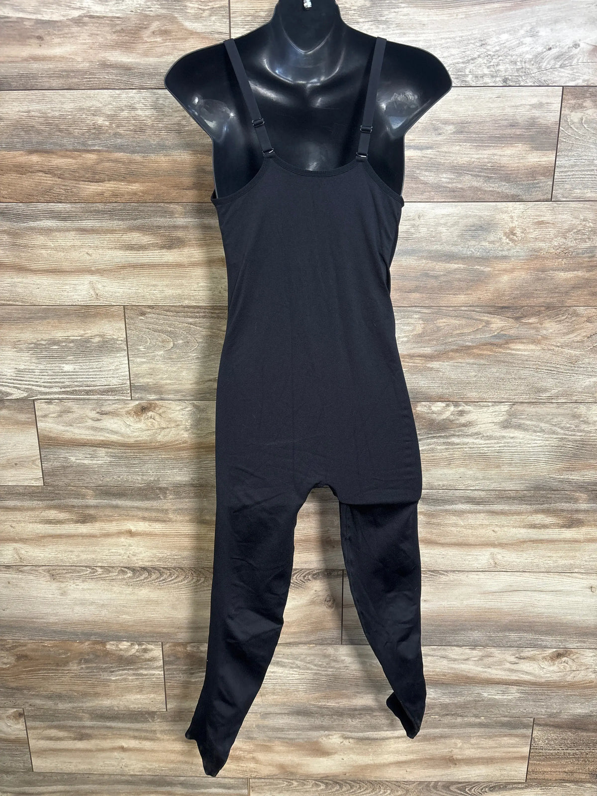 Black maternity nursing tank jumpsuit on a mannequin against a wood wall