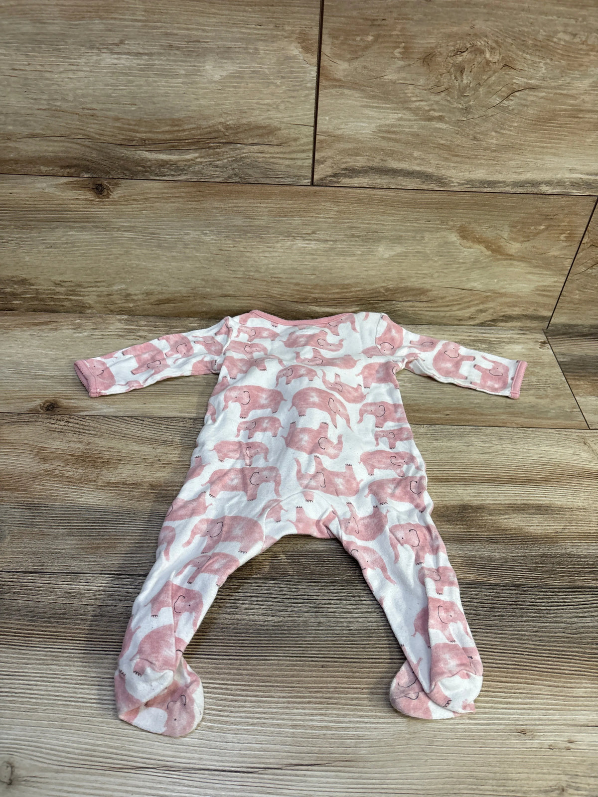 White Just One You baby sleeper with pink elephant print on wood background