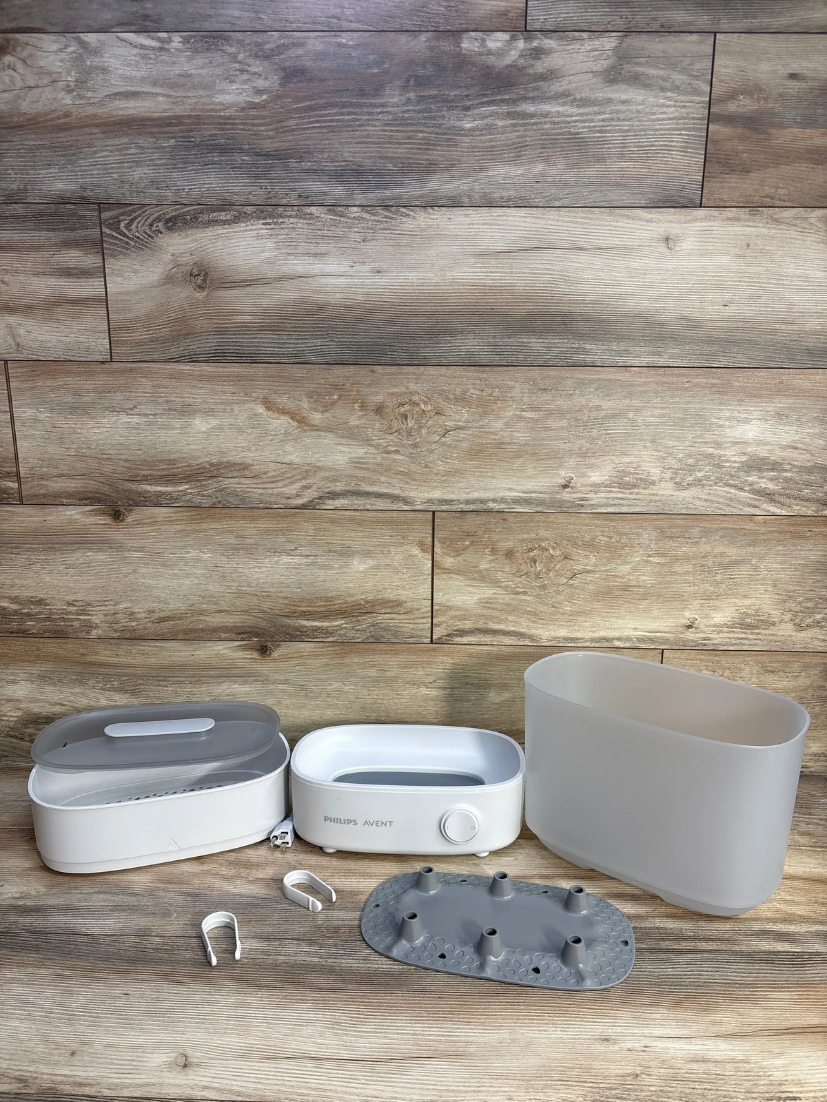 Front view of Philips Avent Advanced Electric Steam Sterilizer showing separate parts on a wood-patterned floor