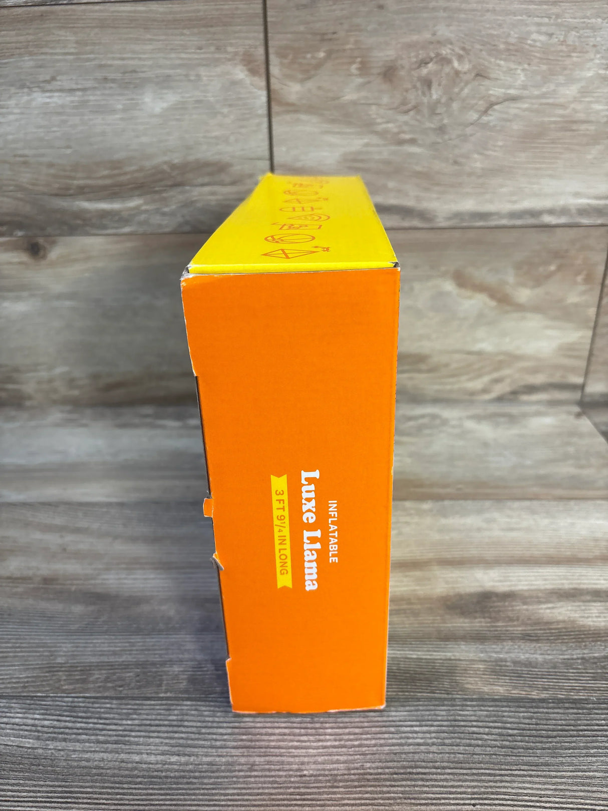 Inflatable Luxe Llama toy box, orange and yellow, 3 ft 9 in long, on wood background
