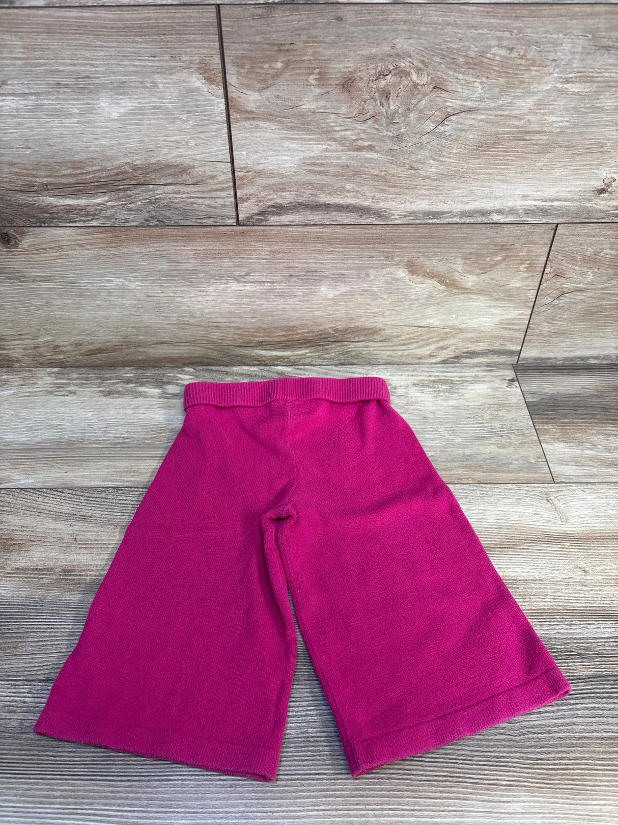 Magenta toddler knit pants with wide legs on wood floor background