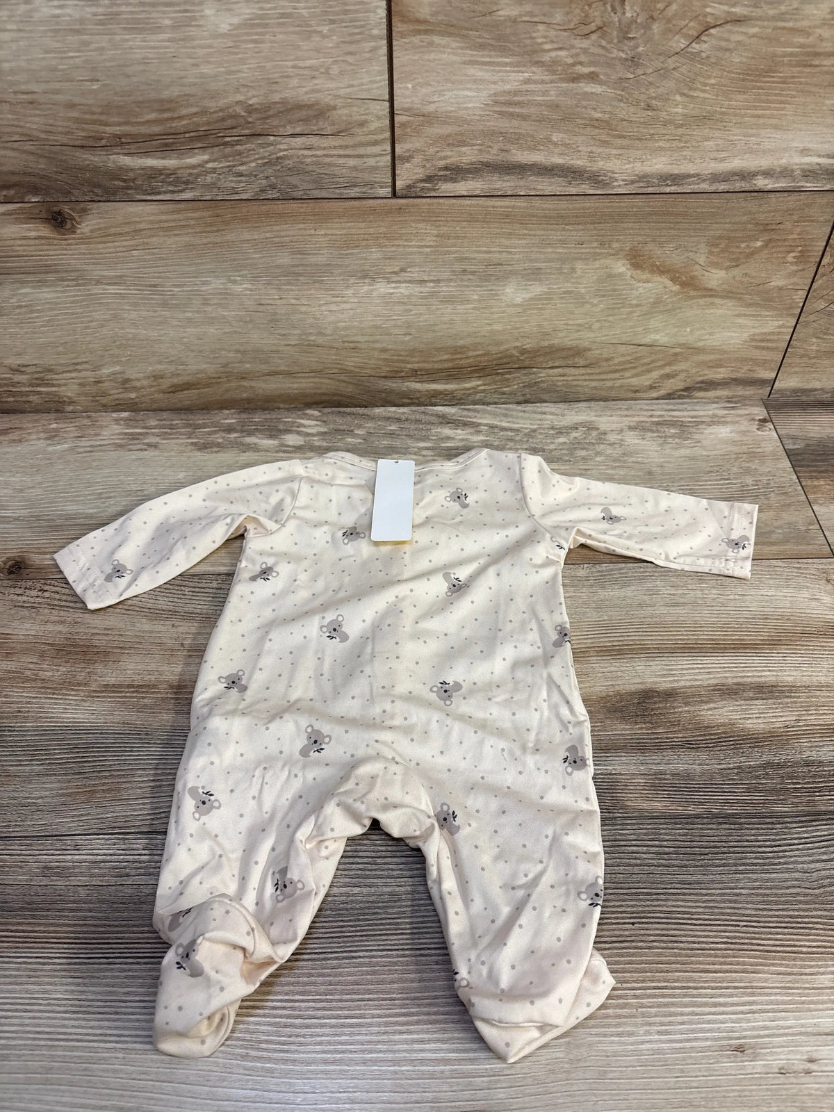 Front view of NEW Shien snap sleeper showcasing beige fabric, gray mouse print, long sleeves, and footed legs on wood background