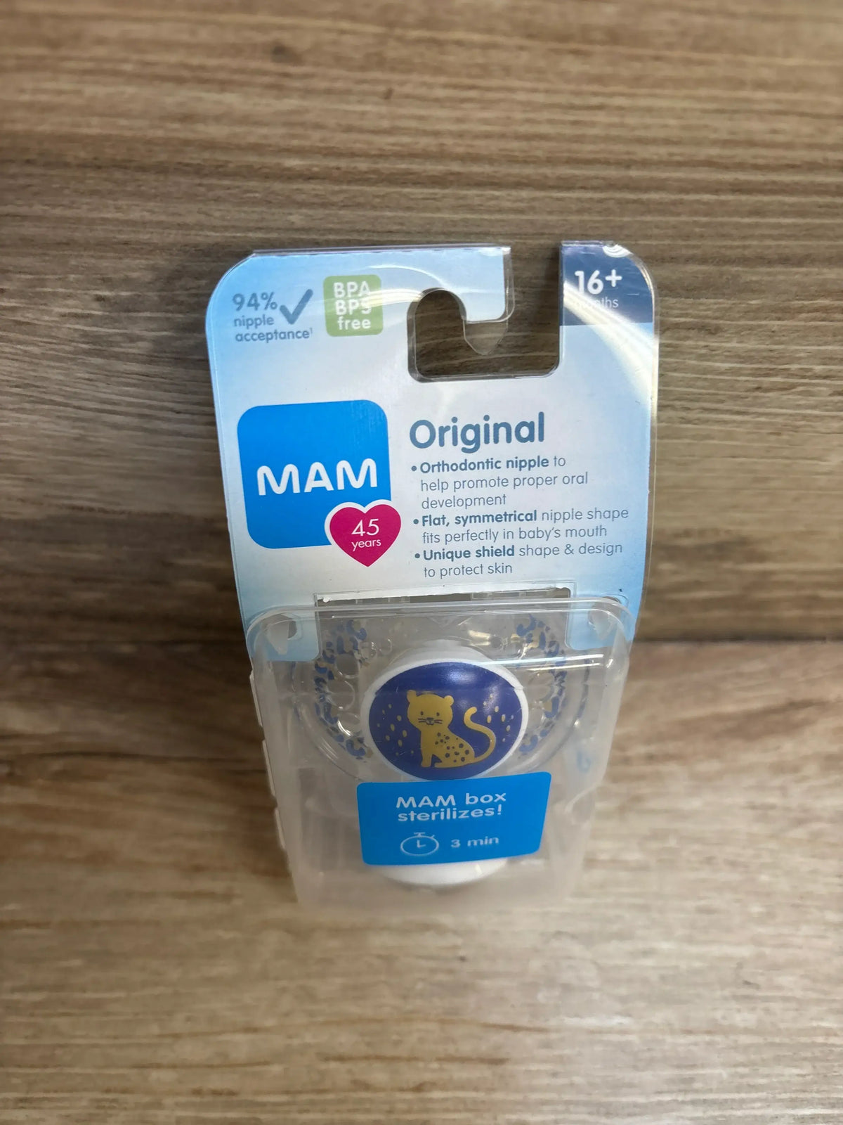 MAM orthodontic baby pacifier with cat design in BPA free packaging on wood surface