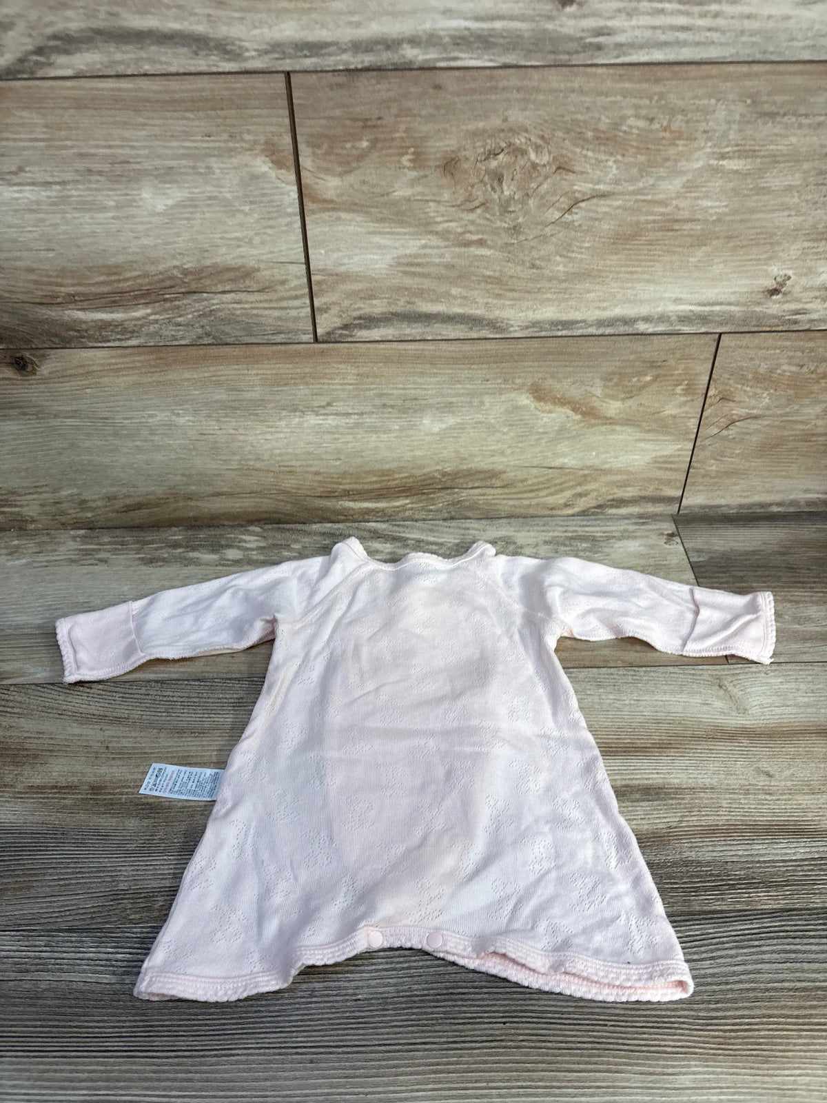 Flat lay of pink Agabang pointelle kimono romper with long sleeves and crotch snaps on wood background