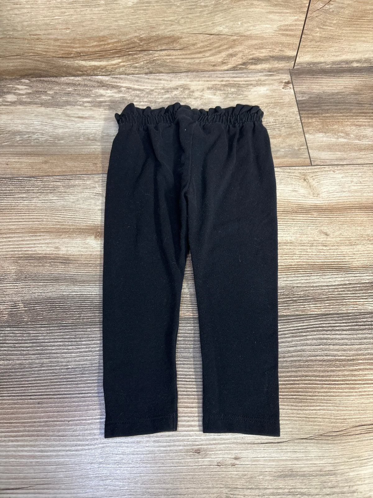 Cat & Jack black baby leggings size 12m laid flat on a wooden floor